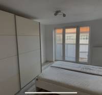 Ein Zimmer in einer 2-Zimmer-Wohnung mit Bett, Einbauschrank und französischem Fenster.