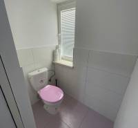 Badezimmer in einer 2-Zimmer-Wohnung mit einer rosa Toilette und weißen Fliesen.