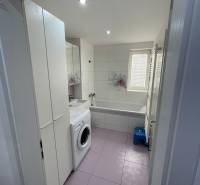 Badezimmer in einer 2-Zimmer-Wohnung mit Waschmaschine, Badewanne, Waschbecken und Stauraum.