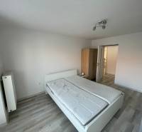 Schlafzimmer in einer 2-Zimmer-Wohnung mit Bett, Schrank und weißen Wänden.