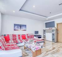 Wohnzimmer in einer 2-Zimmer-Wohnung mit einem bunten Sofa und einem Fernseher, hellem Interieur.
