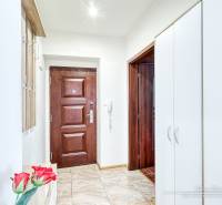 Eingangsbereich einer 2-Zimmer-Wohnung mit Holz- und weißen Schränken und Fliesenboden.