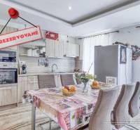 Küche in einer 2-Zimmer-Wohnung mit Tisch, Geräten und dem Schild 