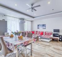 Geräumiges Wohnzimmer mit Esstisch in einer 2-Zimmer-Wohnung, helle Wände und gemustertes Sofa.