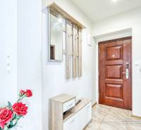 Eingangshalle in einer 2-Zimmer-Wohnung mit Holztüren und Spiegel, dekoriert mit roten Blumen.