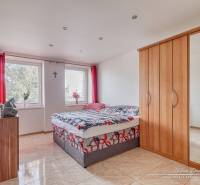 Schlafzimmer in einer 2-Zimmer-Wohnung mit Bett, Kleiderschrank und Fernseher an der Wand.