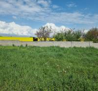 Grünes Grundstück umgeben von einer Mauer mit Blick auf ein gelbes Feld in Cabaj-Čápor. Grundstücke - Wohnen.