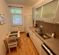 Küche in einer 2-Zimmer-Wohnung mit Esstisch, weißen Schränken und Geräten.