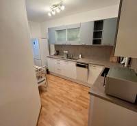 Küche in einer 2-Zimmer-Wohnung mit Holzboden, weißen Möbeln und Geräten.