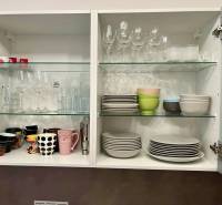 Ein offener Küchenschrank mit Gläsern, Tassen und Tellern in einer 2-Zimmer-Wohnung.