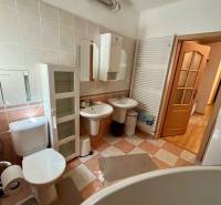 Badezimmer einer Zweizimmerwohnung mit Sanitäranlagen, Schränken und großer Badewanne.