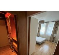 Schlafzimmer in einer 2-Zimmer-Wohnung mit Einbauschrank und Bett, helle Vorhänge.