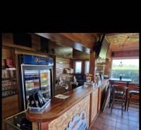 Holzinterieur von Gastronomieräumen mit Bar, Kühlschrank und Fernseher.