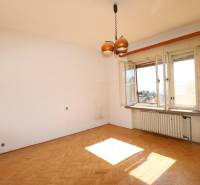 Ein Zimmer in einem Einfamilienhaus mit Holzboden, Heizkörper und offenem Fenster.