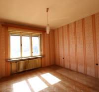 Ein Zimmer mit Parkettboden und Fenster in einem Einfamilienhaus hat Tapeten in orange Farbe.