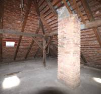 Der Dachboden eines Einfamilienhauses mit einer Holzdachkonstruktion und einem Schornstein aus Ziegeln.