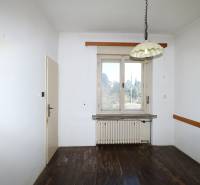 Ein Zimmer mit weißen Wänden, Holzboden, Heizkörper und Fenster in einem Einfamilienhaus.
