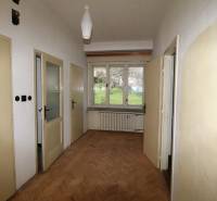 Der Flur in einem Einfamilienhaus mit Holzboden, drei Türen und einem Fenster mit Heizkörper.