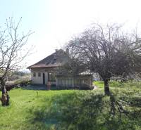Ein Einfamilienhaus in der Jalovcova-Straße in Bratislava - Koliba mit einem Rasen-Grundstück und Bäumen.