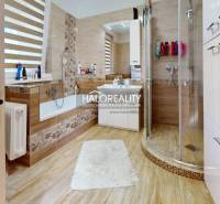 Badezimmer in einem Einfamilienhaus mit Badewanne, Dusche und Waschbecken, warme Holztöne.
