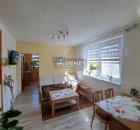 Wohnzimmer in einem Einfamilienhaus mit hellen Vorhängen, einem Holztisch und einem Sofa.