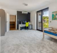 Ein Zimmer in einem Einfamilienhaus mit einem Bett, einem Schreibtisch, einem Balkon und einer Weltkarte an der Wand.