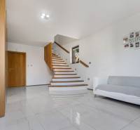 Eine Treppe im Einfamilienhaus mit einem Holzgeländer, einem weißen Sofa und Holzmöbeln.