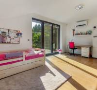 Kinderzimmer in einem Einfamilienhaus mit Bett, Schreibtisch und Balkontür.