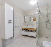 Ein Badezimmer in einem Einfamilienhaus mit einer geräumigen Dusche und einem Waschbecken mit zwei Wasserhähnen.