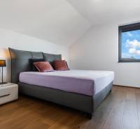 Schlafzimmer im Einfamilienhaus mit großem Bett, Nachttisch und Fenster.