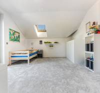 Kinderzimmer im Einfamilienhaus mit Bett, Teppich und Dachfenster.
