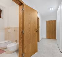 Flur im Einfamilienhaus mit offener Tür zum Badezimmer mit hängendem WC und Bidet.