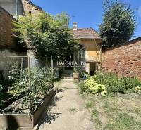 Der Hof eines Einfamilienhauses in Rimavská Sobota mit einem Garten und einer Ziegelmauer.