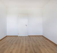 Ein leerer Raum mit Holzboden und weißen Wänden in einer 3-Zimmer-Wohnung.