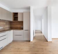 Küche mit Holzelementen und Flur in einer 3-Zimmer-Wohnung, helle und minimalistische Lösung.