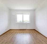 Ein leerer Raum mit Holzboden und einem großen Fenster in einer 3-Zimmer-Wohnung.