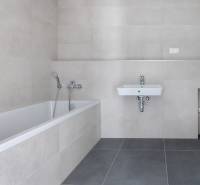 Badezimmer mit Badewanne und Waschbecken in einer 3-Zimmer-Wohnung mit neutralen Fliesen.