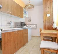 Küche in einer 3-Zimmer-Wohnung mit Holzmöbeln, Herd und Mikrowelle.