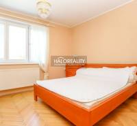 Helles Schlafzimmer in einer 3-Zimmer-Wohnung mit Bett, Holzboden und Vorhängen.