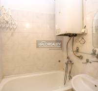 Badezimmer mit Badewanne und Boiler in einer 3-Zimmer-Wohnung, weiße Fliesen, Waschbecken.