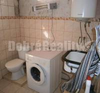 Badezimmer in einem Einfamilienhaus mit Waschmaschine, Toilette und Waschbecken.