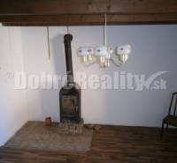 Innenraum eines Einfamilienhauses mit Ofen, Holzstuhl und Wandleuchte.