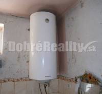 Ein elektrischer Boiler in einem Einfamilienhaus mit Wandverkleidung und kleinem Fenster.