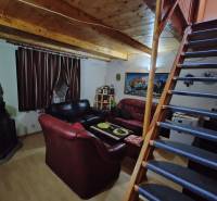 Interieur einer Hütte mit Holzbalkendecke, Sofas und einer Treppe, die in den oberen Stock führt.