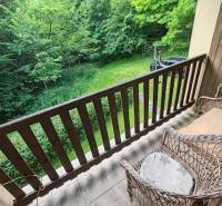 Der Balkon der Hütte mit Korbstühlen und Blick auf den Garten und das Grün.