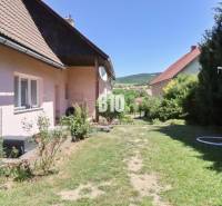 Garten beim Einfamilienhaus in der Stadt Podhradie mit Rasen und umliegender Natur.