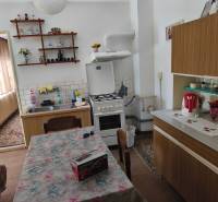 Küche in einem Einfamilienhaus mit Esstisch, Küchenzeile und Dekorationen auf dem Regal.