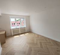 Ein Zimmer mit Holzboden und einem großen Fenster in einer 2-Zimmer-Wohnung.