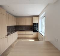 Küche in einer 2-Zimmer-Wohnung mit Holzschränken und eingebauten Geräten.