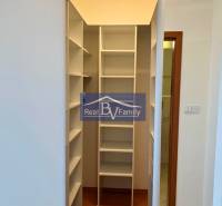 Ein Kleiderschrank in einer Einzimmerwohnung mit weißen Regalen und Holzboden.